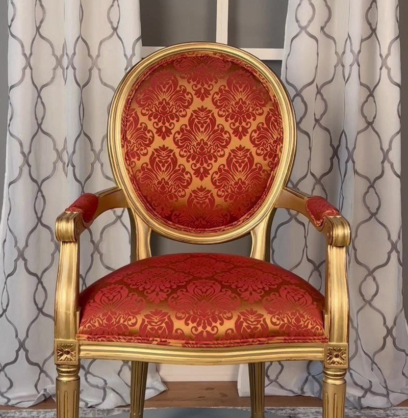 Front view of a Sigla Louis XVI oval-back armchair in gold with red damask upholstery