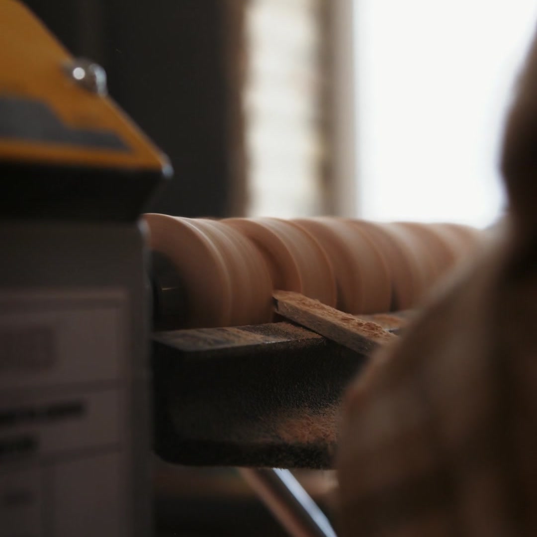 Wood spinning on a lathe while a craftsman shapes it