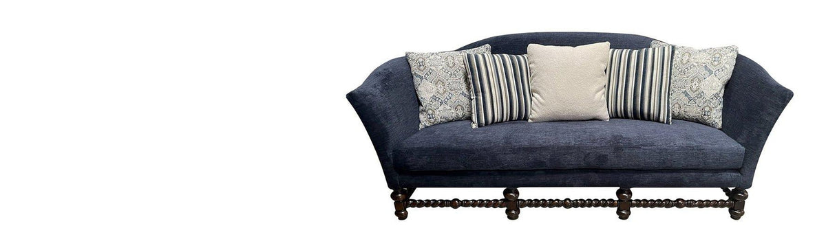 Navy upholstered sofa with striped pillows and turned wood legs