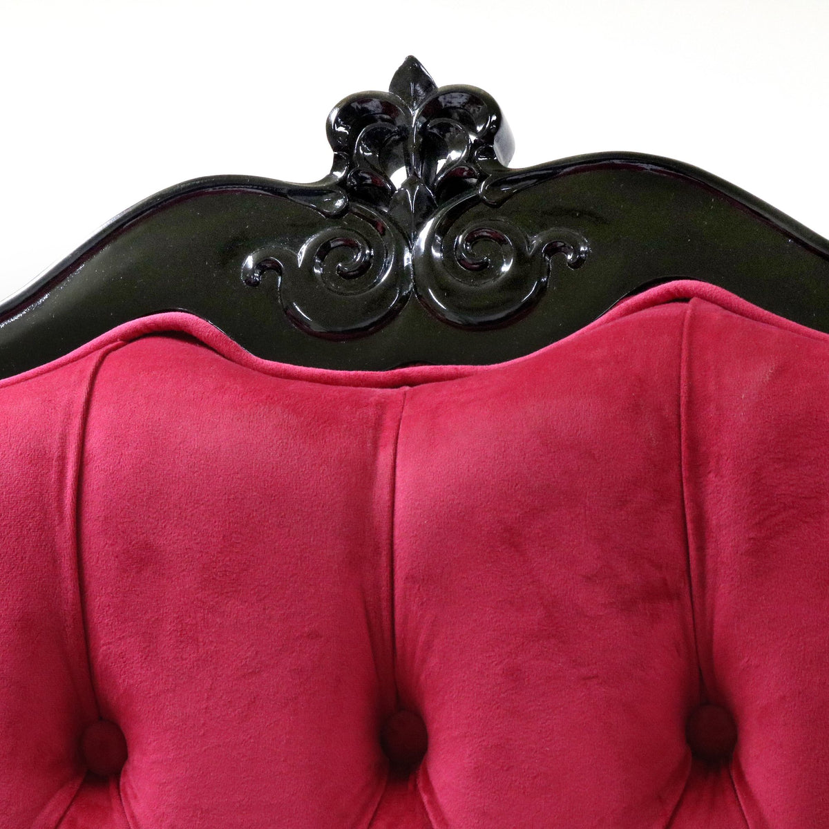 Tufted pink velvet chair back with a carved black crest