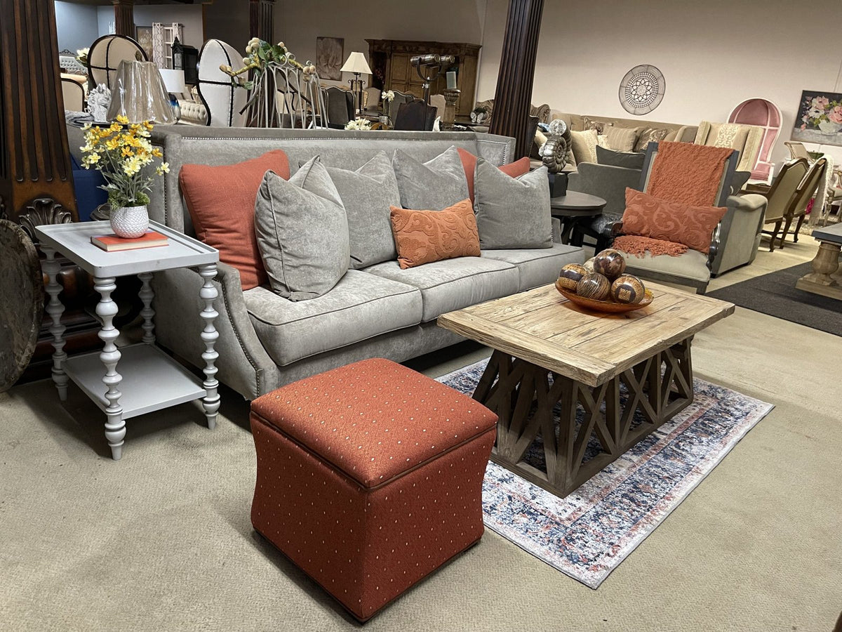 Gray sofa with rust accents and a reclaimed wood coffee table in the Sigla showroom