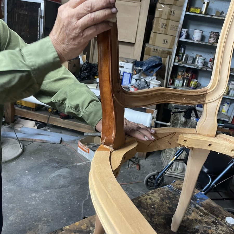 Craftsman fitting a hand-shaped wooden chair frame in the Sigla workshop